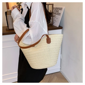 Detail of woven straw tote bag with brown leather shoulder strap in a cozy cafe setting