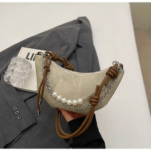 Detail of beige canvas croissant bag with braided leather strap and pearl chain accent