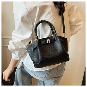 Detail of black lychee grain leather bucket bag with silver metal buckle and top handle