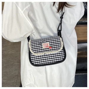 Detail showing checkered canvas crossbody bag with delicate lace trim and bow accent