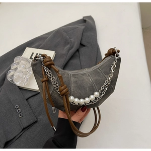 Detail of grey denim hobo bag with pearl chain accents and knotted brown leather strap