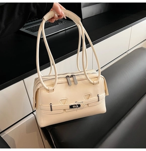 Detail of beige minimalist shoulder bag featuring triple zippers and metallic buckle lock
