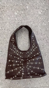 Detailed close-up of a vintage hobo bag featuring dense silver rivets and soft leather