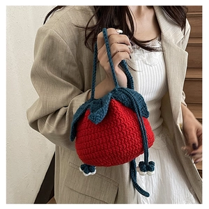 Close-up of handmade red strawberry knitted handbag with green leaf detail and handle