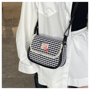 Detail of gingham shoulder bag with lace trim, bow, and cute patch on model