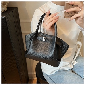 Detail of black lychee grain leather bucket bag with silver buckle held by a model