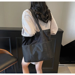 Detalle del bolso tipo cubo negro con compartimentos de malla y correas de lona gruesa