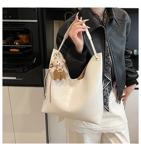 Detail view of cream white PU leather hobo bag featuring a cute teddy bear charm pendant