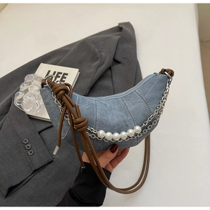 Close-up of light blue denim crescent bag with silver chain and five large pearls