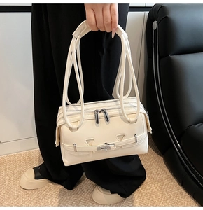 Detail of cream white shoulder bag featuring triple zippers and silver metal twist lock