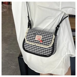 Detail of plaid canvas crossbody bag featuring lace trim and a cute strawberry pendant