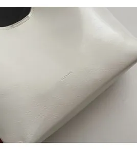 Detailed view of the creamy white leather texture and CLEARK logo on a shoulder bag