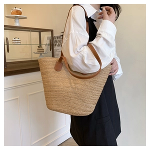 Detailed weave of a large straw tote bag with brown leather straps on a female model