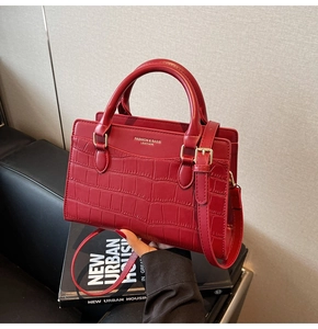 Detail of red crocodile pattern handbag featuring gold hardware and logo branding