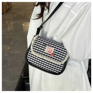 Close-up of black and white plaid canvas bag with lace trim and strawberry charm