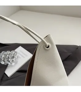 Detail of premium beige leather tote bag featuring precise stitching and metal eyelets