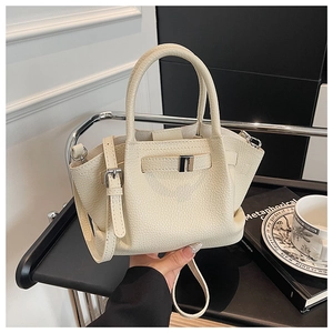 Detail of cream pebbled leather bucket bag featuring a gold buckle and slim strap