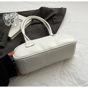 Detail shot of white Boston style bag featuring textured leather and minimal double handles