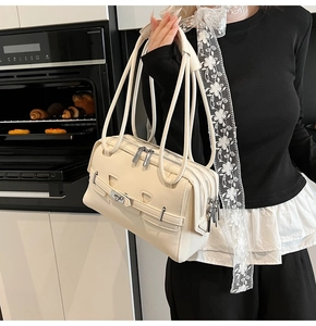 Detail of cream leather shoulder bag showing three zipper compartments and silver hardware