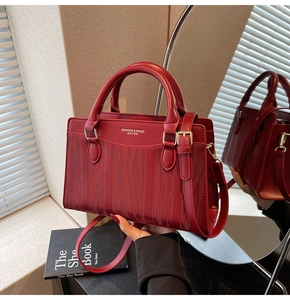 Macro shot of wavy textured burgundy PU leather tote with elegant golden metal hardware