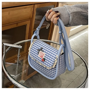 Detail of blue plaid mini bag with lace trim, strawberry charm and bow decoration