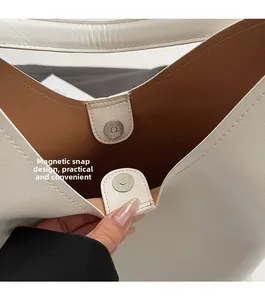Detail of magnetic closure on white leather tote bag with brown lining texture