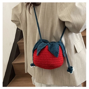 Detail view of handmade knit tomato shaped shoulder bag with blue leaves and strap