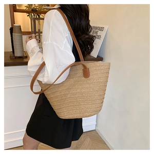 Detailed view of hand-woven straw tote bag with brown leather handles for beach vacation