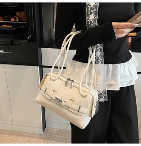 Detail showing the cream leather shoulder bag with metallic lock buckle and decorative straps