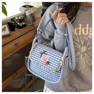 Close-up of blue gingham crossbody bag with white lace trim and cute strawberry charm