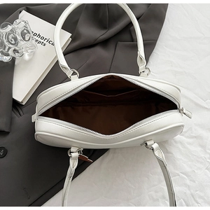 Macro shot showing white faux leather bag interior with brown lining and zipper