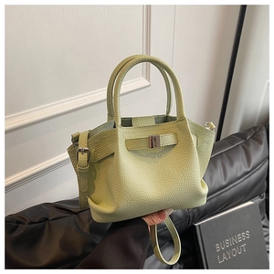Close-up of pistachio green pebbled leather bucket bag with top handles and strap