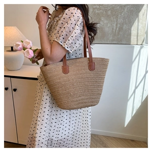 Detail of hand-woven straw tote bag with brown faux leather straps and fine texture