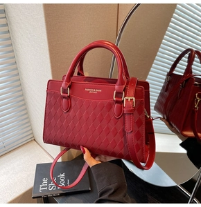 Close-up of red tote bag with diamond pattern, gold lettering and polished hardware