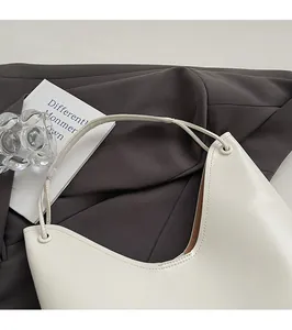 Close-up of white minimalist matte tote bag with elegant metal buckle on dark fabric