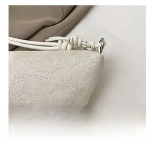 Detailaufnahme des eleganten weißen Jacquard-Blumenstoffs und Webgriffs der Schultertasche