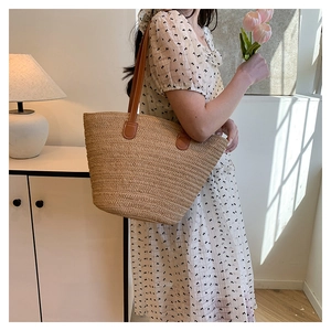 Detailed view of natural straw tote bag with brown faux leather straps for summer beach