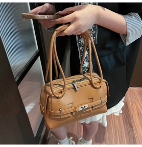 Detail view of tan leather shoulder bag with silver turn-lock and dual handles