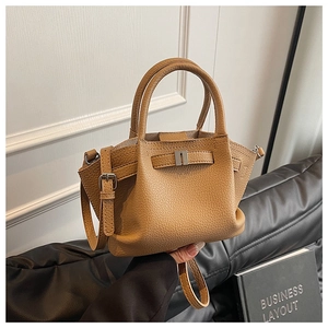 Detailed view of the lychee grain texture and metal buckle on camel bucket bag
