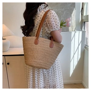 Detailed texture of straw woven tote bag featuring brown faux leather shoulder straps