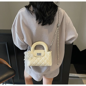 Quilted off-white handbag with silver chain and lace pearl charm shown from the back