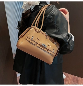 Detail view of tan leather tote bag featuring metal lock closure and belt decoration