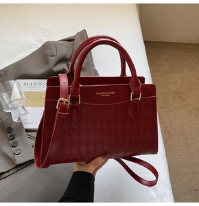 Close-up of wine red quilted leather handbag with gold hardware and embossed text