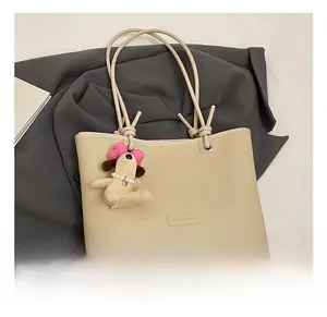 Detail of beige lychee pattern leather tote bag featuring cute plush puppy charm