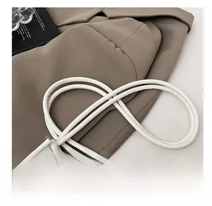Detail einer weißen Ledertasche mit schickem zylindrischem Knotendesign am Schultergurt