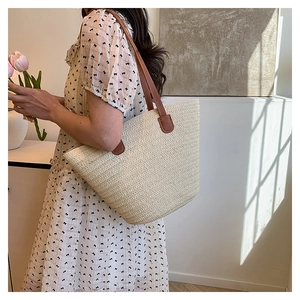 Detail of cream woven tote bag showing fine texture and brown leather handles