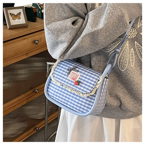 Close-up of gingham canvas saddle bag with lace trim and cute strawberry charm details