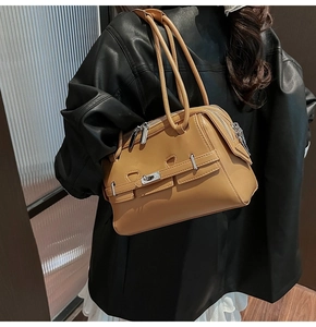 Detail of tan leather shoulder bag with silver turn-lock and dual handles on model
