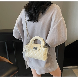 Detail of cream quilted crossbody bag with silver twist lock and lace pearl charm