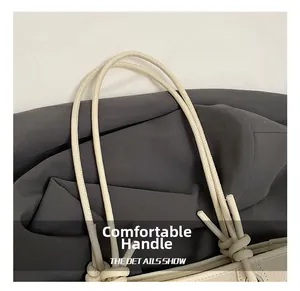 Detail of minimalist cream tote bag showing soft pebbled leather and knotted strap handle